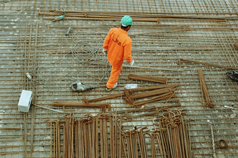 Worker in orange uniform, construction materials.