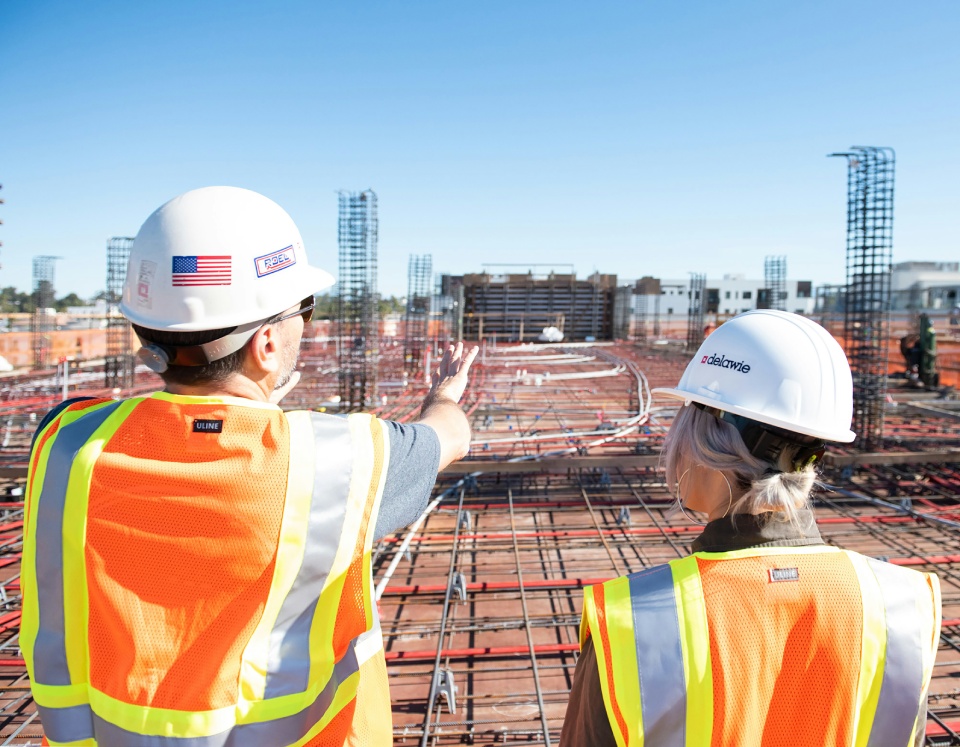 Two construction workers discussing building framework.