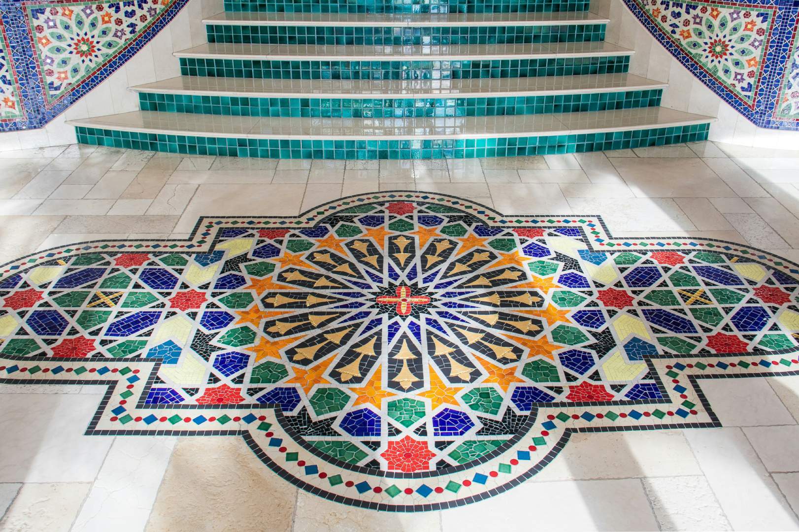 Colorful mosaic design near tiled stairs.