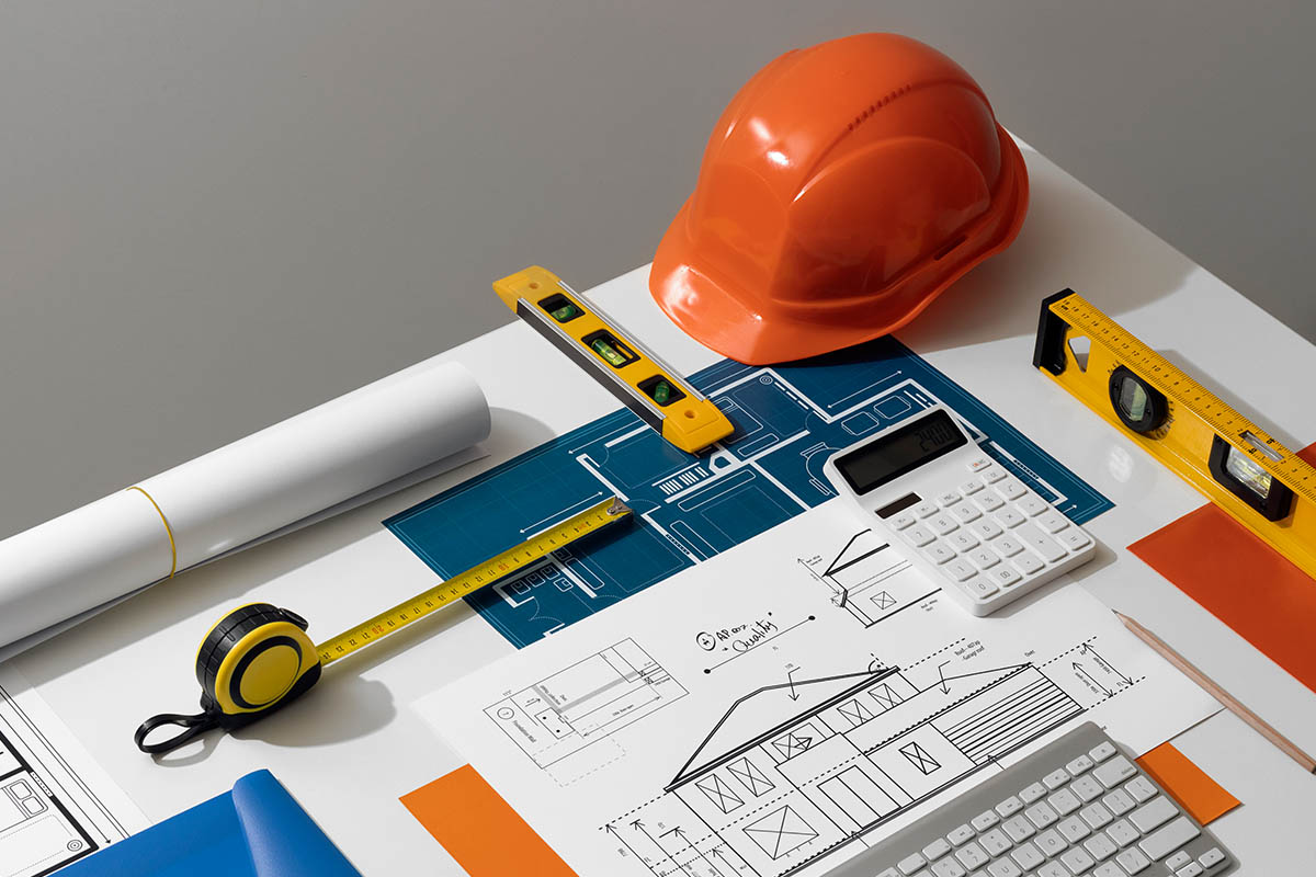 Construction tools, blueprints, helmet on desk.