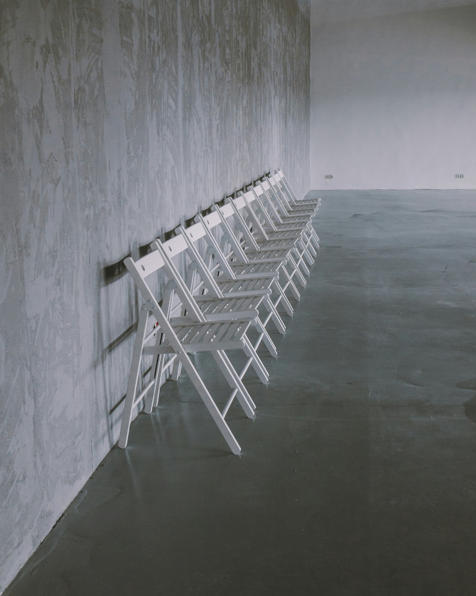 White chairs lined up against textured wall.